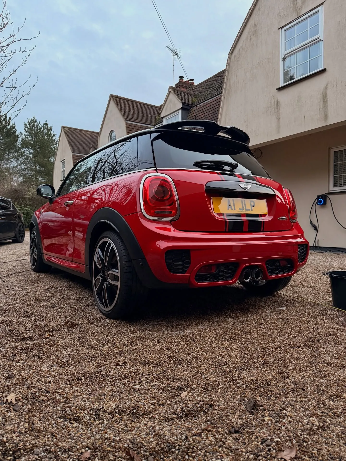Red Mini Cooper with a black roof, freshly valeted on a gravel driveway